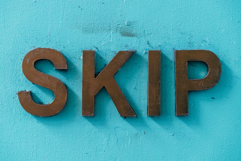 Close-up of three uppercase metal letters spelling 'SKIP' mounted on a bright turquoise painted wall. The letters are made of weathered, rust-colored metal with a textured, matte finish, showing signs of slight corrosion and irregularities. They are positioned horizontally, with the letters evenly spaced, and occupy the central area of the image. The wall surface behind them has a rough, slightly textured appearance with visible brush strokes and small cracks. The lighting is even, highlighting the contrast between the vibrant wall and the earthy tones of the metal letters, reflecting a straightforward and professional setting related to waste management or alternative rubbish disposal options, as indicated by the context of rubbish removal services. The composition emphasizes the signage, possibly indicating a designated area for skip placement or marking a storage zone, aligning with the themes of private waste handling and on-site clearance, typical in waste collection environments managed by companies like Waste Collection Paddington.